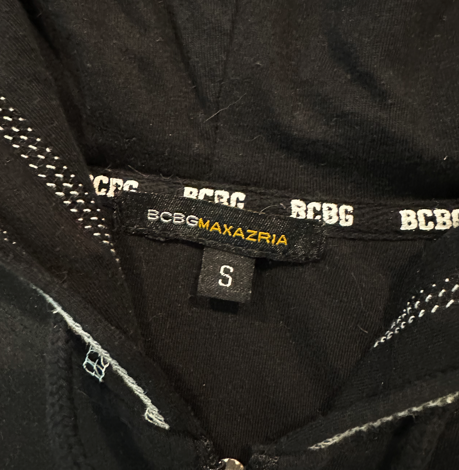 BCBGeneration Black Zip-Up Hoodie with White StitchingSlip into something cozy and chic! The BCBGeneration Black Zip-Up Hoodie with White Stitching is the perfect addition to your wardrobe, combining go-to style with a BCBGeneration Black Zip-Hoodie